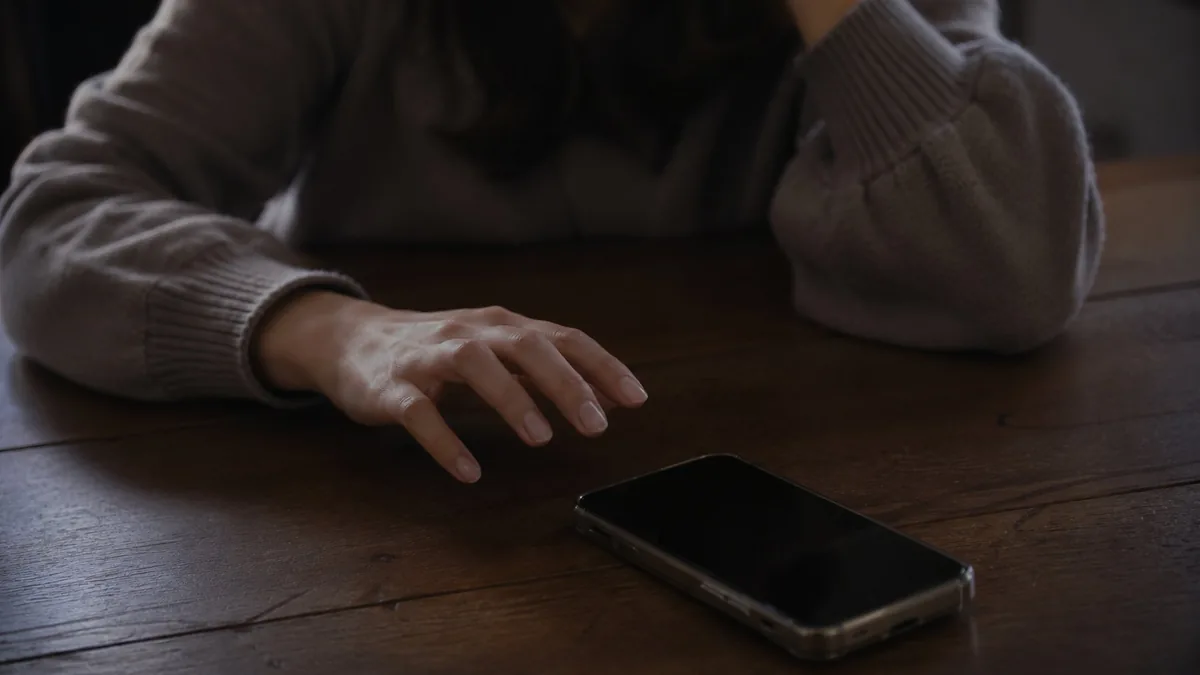 夫のスマホを勝手に見ようとして迷う妻の手