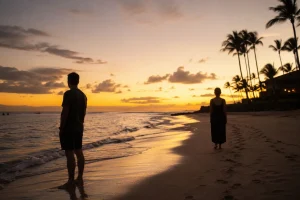 ハワイの浜辺で距離を置いて立つ夫婦のシルエット、夕暮れの光