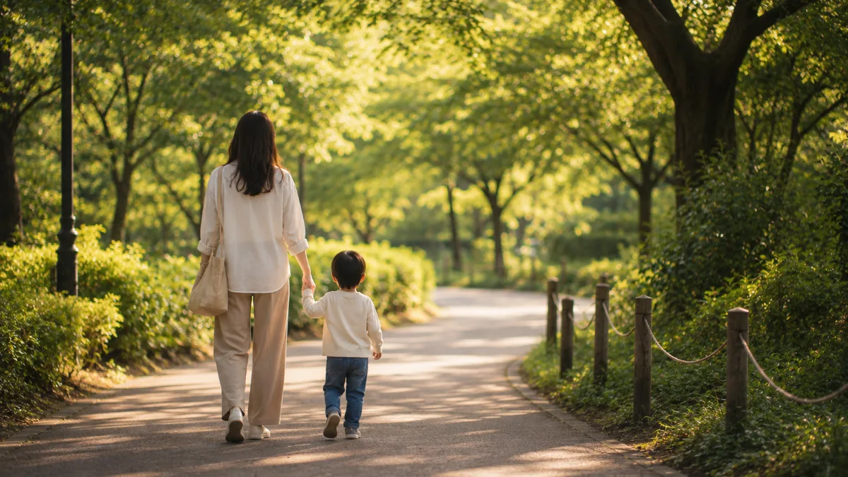 子どもと手をつないで公園を歩く母親の後ろ姿。どちらの道でも子どもと生活を守る