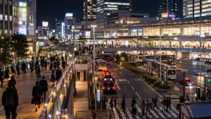 夜のターミナル駅前のペデストリアンデッキとバスロータリーを行き交う人々