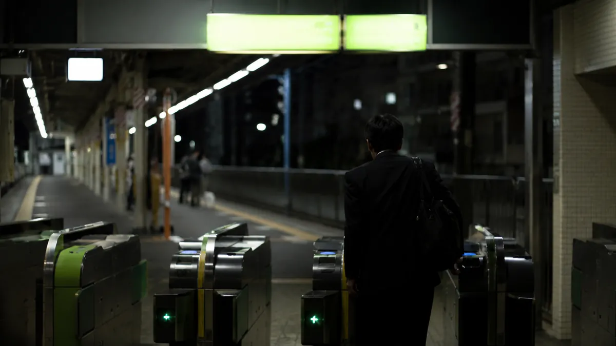 夜遅く駅の改札を抜ける会社員の後ろ姿