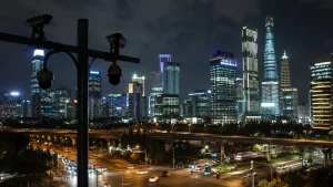夜の上海のスカイラインと交差点の支柱に取り付けられた複数の監視カメラ