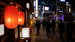 夜の新橋、赤提灯が並ぶ飲食店街を歩くスーツ姿の会社員たち