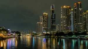 夜のアジアの都市、川沿いに並ぶ高層コンドミニアムと水面の反射