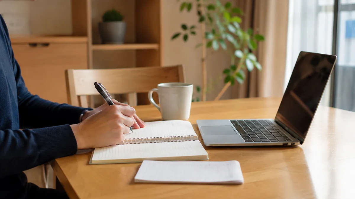 自宅のダイニングでノートPCとメモを前に相談内容を書き出す手元
