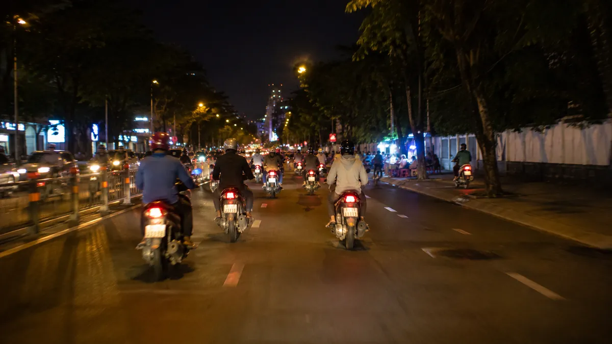 夜、前を走るバイクを後方から追うベトナムの通りの視点